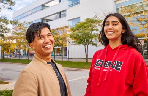 Two students laughing outside the Dahdeleh Building at York University