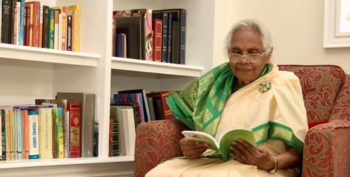 Varathaledchumy Shanmuganathan sitting in her living room reading a book